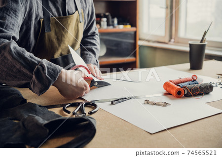 Before start working directly with the leather, the shoe manufacturer makes a preliminary pattern out of paper 74565521