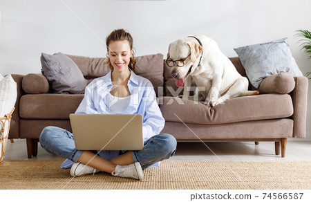 Cheerful woman and dog in glasses surfing laptop 74566587