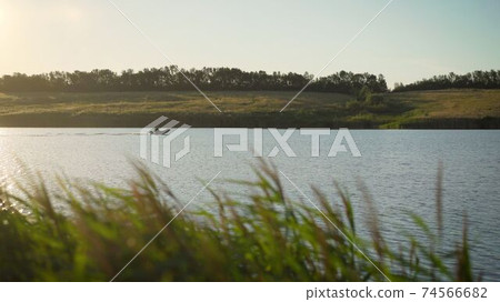 A man rides a motor boat in an inflatable boat on a lake at sunset. Fisherman rides a motor boat on the river. A man rides a motor boat in an inflatable boat on a lake at sunset. Fisherman rides a motor boat on the river. 74566682
