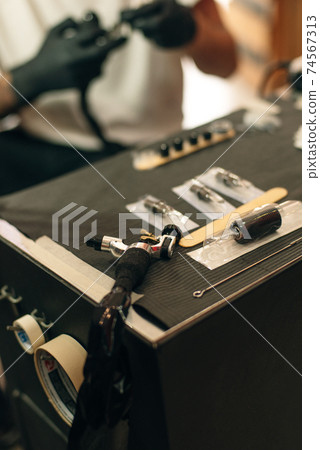 Tattoo artist workplace with machine and bottles with black tattoo ink 74567313