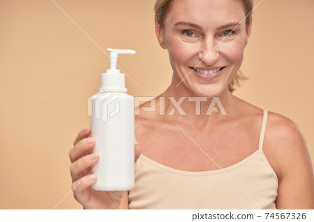 Close up of smiling beautiful woman holding moisturizing body cream Close up of smiling beautiful woman holding moisturizing body cream 74567326