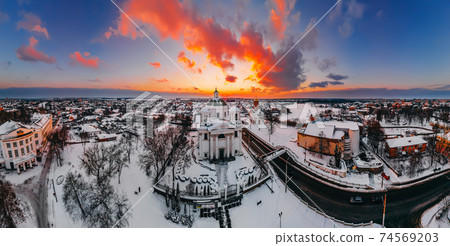 Panoramic aerial view of the cathedral and church in snow-covered small european city at bright winter sunset 74569203