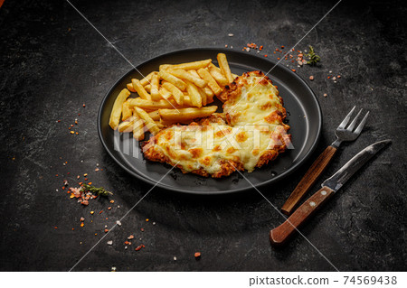 Fast food in a black plate. Golden brown chicken with cheese and french fries 74569438