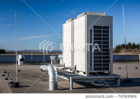 Air vents on the roof of building in functional and operational condition. Around are seen vent pipes and lightning rods. Sky is blue and the background is slightly blurred, focus on ventilation unit. 74569968