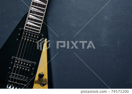 Black V shape electric guitar on dark grunge background. Black V shape electric guitar on dark grunge background. 74571200