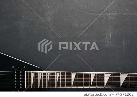 Black V shape electric guitar on dark grunge background. Black V shape electric guitar on dark grunge background. 74571202