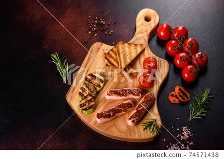 Tasty, fresh sausages grilled with vegetables spices and herbs 74571438