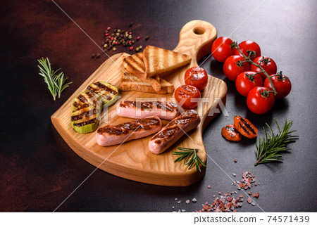 Tasty, fresh sausages grilled with vegetables spices and herbs 74571439