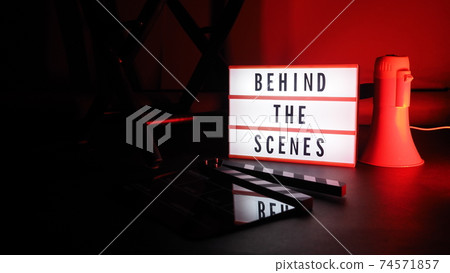 Behind the scenes letterboard text on Lightbox or Cinema Light box. Movie clapperboard megaphone and director chair beside. Background LED color change. static camera in video production studio. 74571857