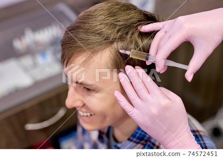 young male person at trichologist office get injections in head skin young male person at trichologist office get injections in head skin 74572451