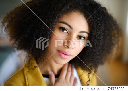 Close-up portrait of beautiful young woman indoors, looking at camera. Close-up portrait of beautiful young woman indoors, looking at camera. 74572631