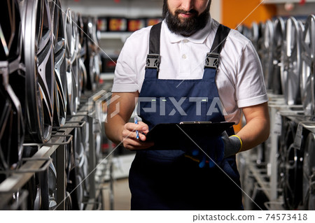 cropped bearded auto mechanic male with paper tablet in hands 74573418