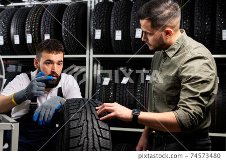 auto mechanic talk about advantages of auto tire to young client in service auto mechanic talk about advantages of auto tire to young client in service 74573480
