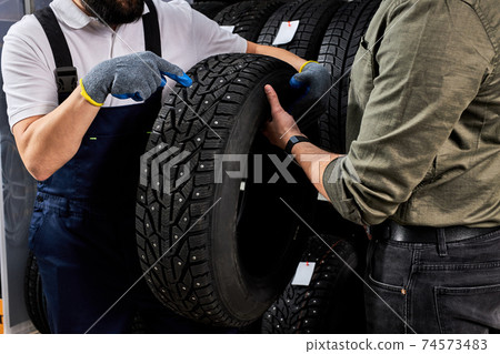 handsome caucasian salesman of tires talking about characteristic of product handsome caucasian salesman of tires talking about characteristic of product 74573483