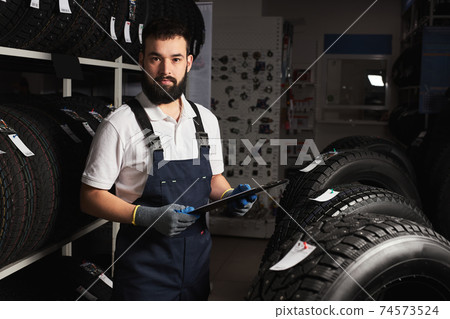 caucasian male mechanic near rack with car tires in auto store caucasian male mechanic near rack with car tires in auto store 74573524