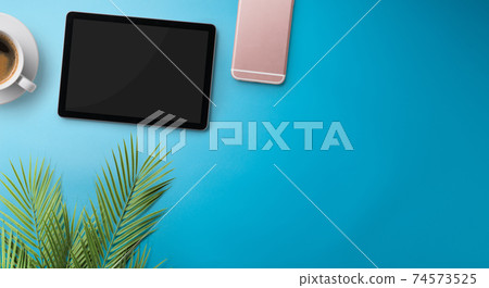 Flat lay top view office desk working space with tablet on blue background. Copy space. Flat lay top view office desk working space with tablet on blue background. Copy space. 74573525