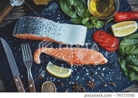 Raw salmon fillet and ingredients for cooking on a dark background Raw salmon fillet and ingredients for cooking on a dark background 74573590