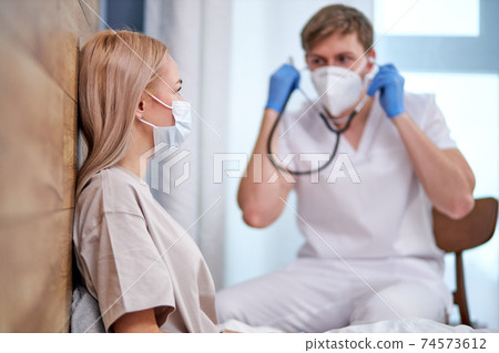 male doctor is going to examine sick patient lying on bed 74573612