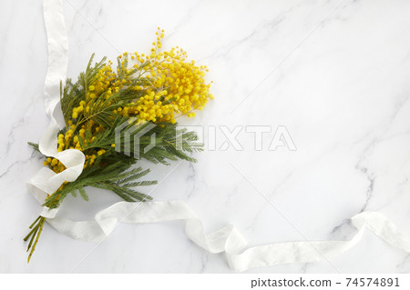 a bouquet of yellow mimosa flowers on a marble background. Concept of women's or mothers day. 74574891