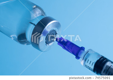 Close-up of filling a syringe with vaccine. A syringe with a needle draws the medicine. Close-up of filling a syringe with vaccine. A syringe with a needle draws the medicine. 74575091