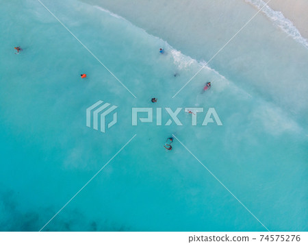 Aerial Drone Shot of Black local African Kids swimming in Turquoise Water of Indian Ocean at Zanzibar island, Nungwi 74575276