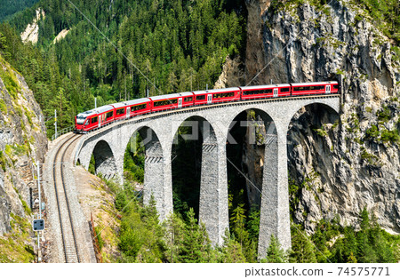 Passenger train crossing the Landwasser Viaduct in Switzerland 74575771
