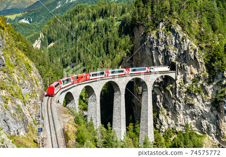 Passenger train crossing the Landwasser Viaduct in Switzerland 74575772