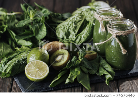 Blended green smoothie with ingredients on the stone board, wooden table Blended green smoothie with ingredients on the stone board, wooden table 74576440