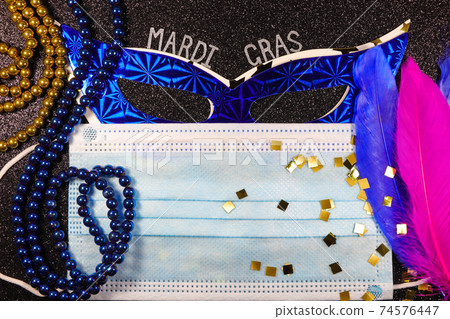 Mardi Gras Masks Behind Medical Facemask With Bead Strings And Feathers 74576447