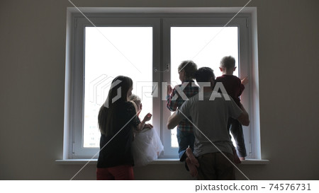 Silhouette of a large family on the background of a window in a new apartment. Silhouette of a large family on the background of a window in a new apartment. 74576731
