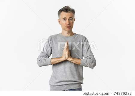 Image of sad middle-aged man begging for help, need something and asking for favour, standing over white background Image of sad middle-aged man begging for help, need something and asking for favour, standing over white background 74579282