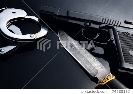 Gun, knife and handcuffs on black background 74580383