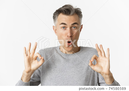 Close-up of impressed middle-aged guy, showing okay signs in approval, like something good, recommending product, standing over white background 74580389