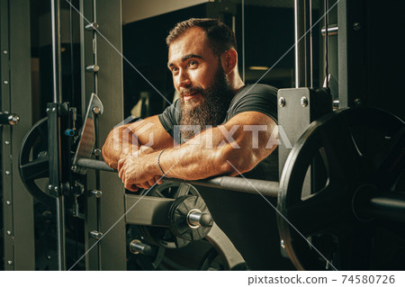 Fit man doing squats in a training machine 74580726
