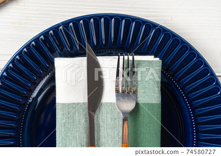 Deep blue ceramic plate with cutlery close up Deep blue ceramic plate with cutlery close up 74580727