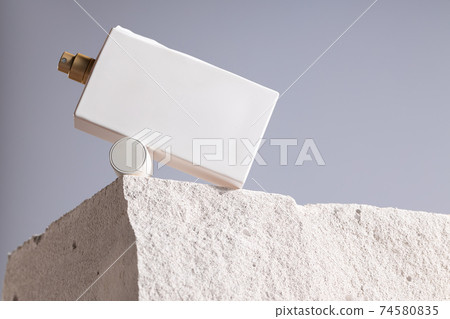 Bottle of perfume on cinder block close up 74580835
