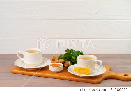 Cup of tea with ginger and mint on wooden table 74580921