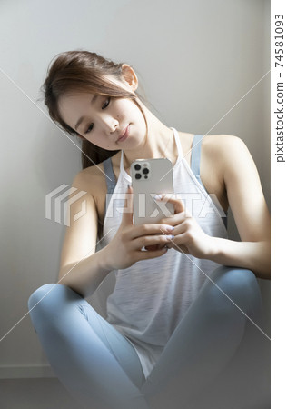 A woman looking at a smartphone in sportswear 74581093