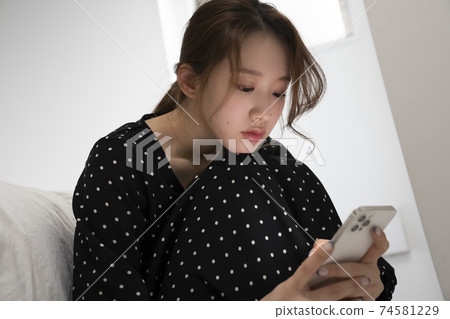 Woman looking at smartphone in the room 74581229