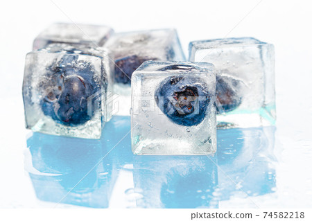 Frozen berries in ice cubes on pink 74582218
