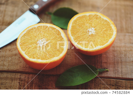 Fresh orange slice and leaves healthy fruits, Orange fruits with leaf kitchen knife on wooden background. 74582884