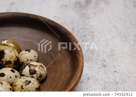 fresh quail eggs from the farm in a plate of brown clay on a gray marble table. fresh quail eggs from the farm in a plate of brown clay on a gray marble table. 74582912