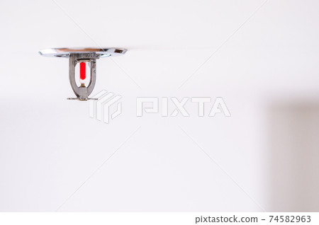 Fire sprinkler detection mounted setting on ceiling in room 74582963