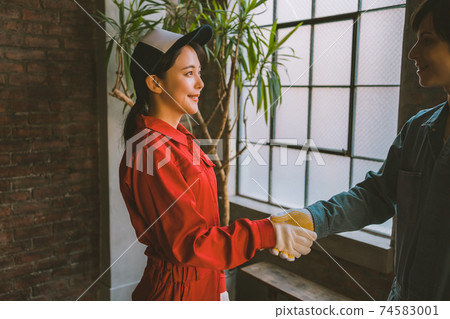 Handshake scene of men and women wearing coveralls 74583001