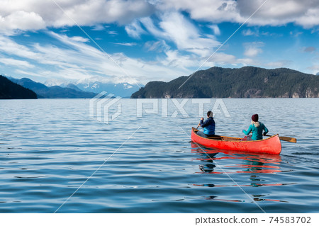 Couple friends canoeing on a wooden canoe Couple friends canoeing on a wooden canoe 74583702