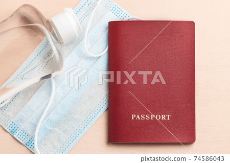 Safe travel during coronavirus pandemic concept. Protective medical mask sanitizer and passport on the table, flatlay Safe travel during coronavirus pandemic concept. Protective medical mask sanitizer and passport on the table, flatlay 74586043