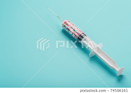 Syringe filled with colorful nano balls on a light blue background. Syringe filled with colorful nano balls on a light blue background. 74586161
