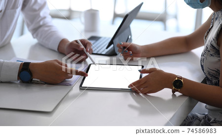 Cropped shot of business people wearing protective mask working on their project with digital tablet at modern office. 74586983
