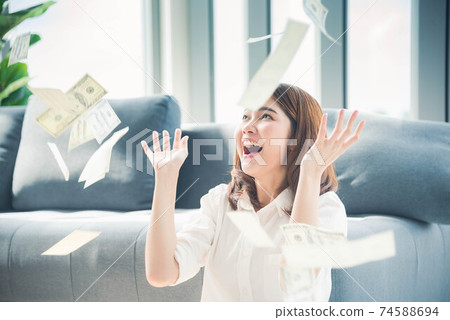 Happy young asian woman holding dollar money and throw in the air celebrate happiness dance 74588694