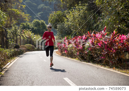 Fitness woman runner running on winter park trail 74589073